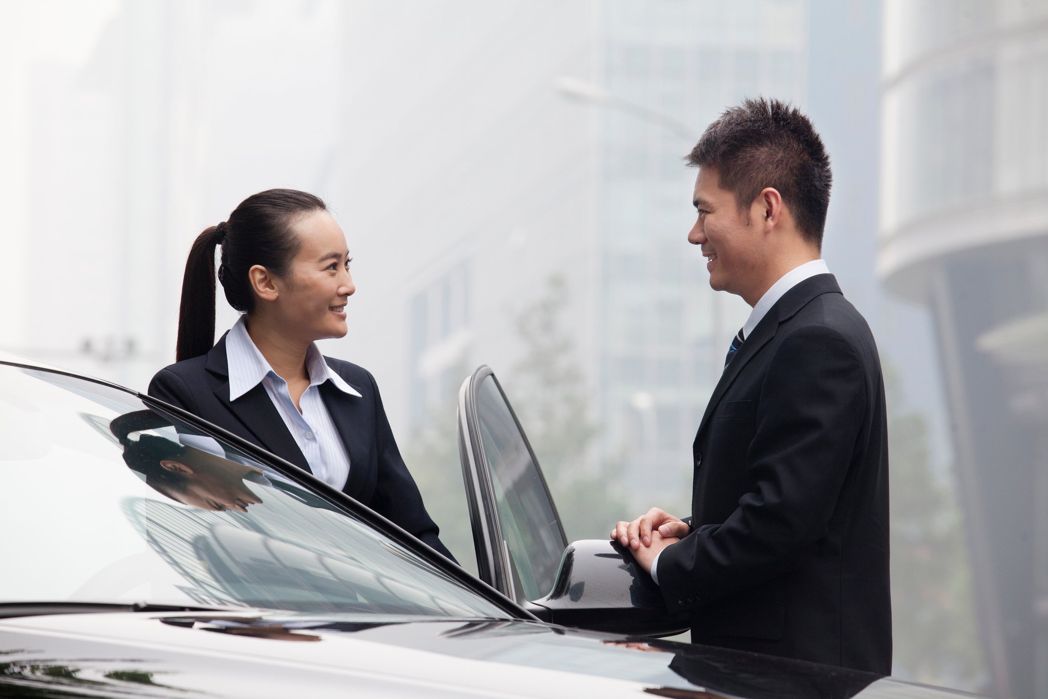 Two people stand near a car.