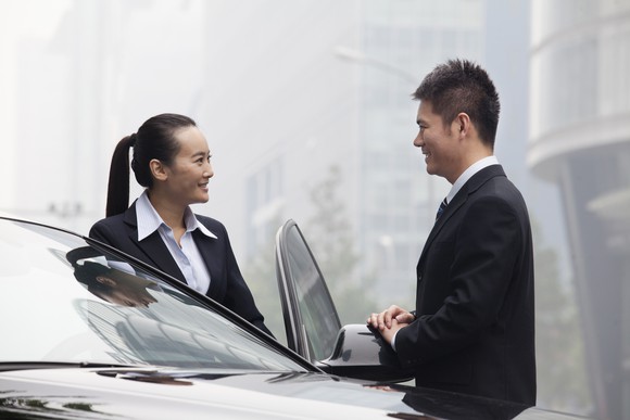 Two people stand near a car.