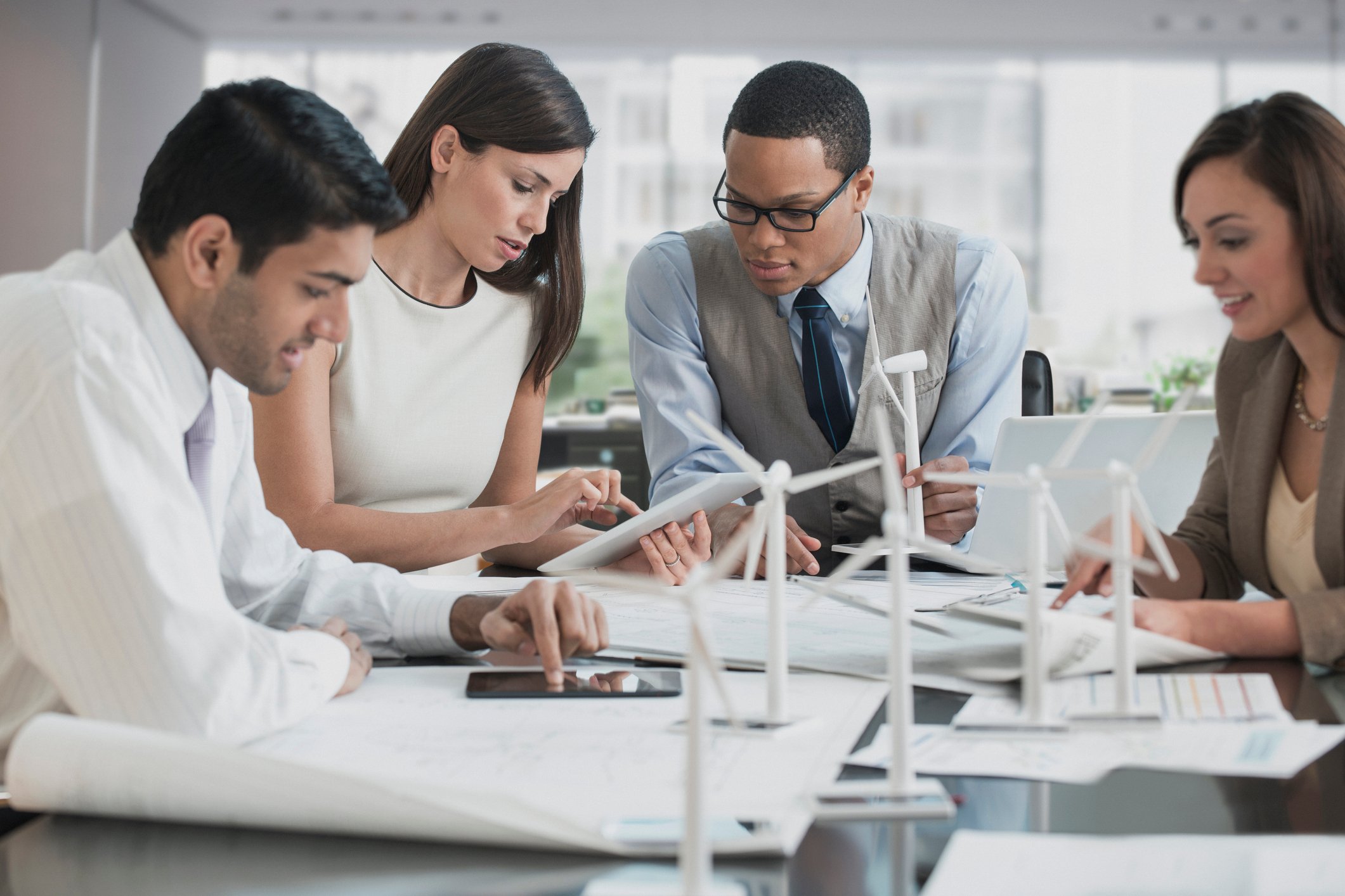 Three businesspeople looking at model of wind farm.
