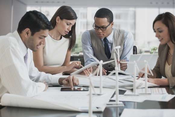 Three businesspeople looking at model of wind farm.