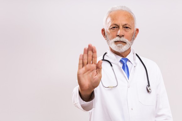 Doctor holding out hand in "stop" gesture. 