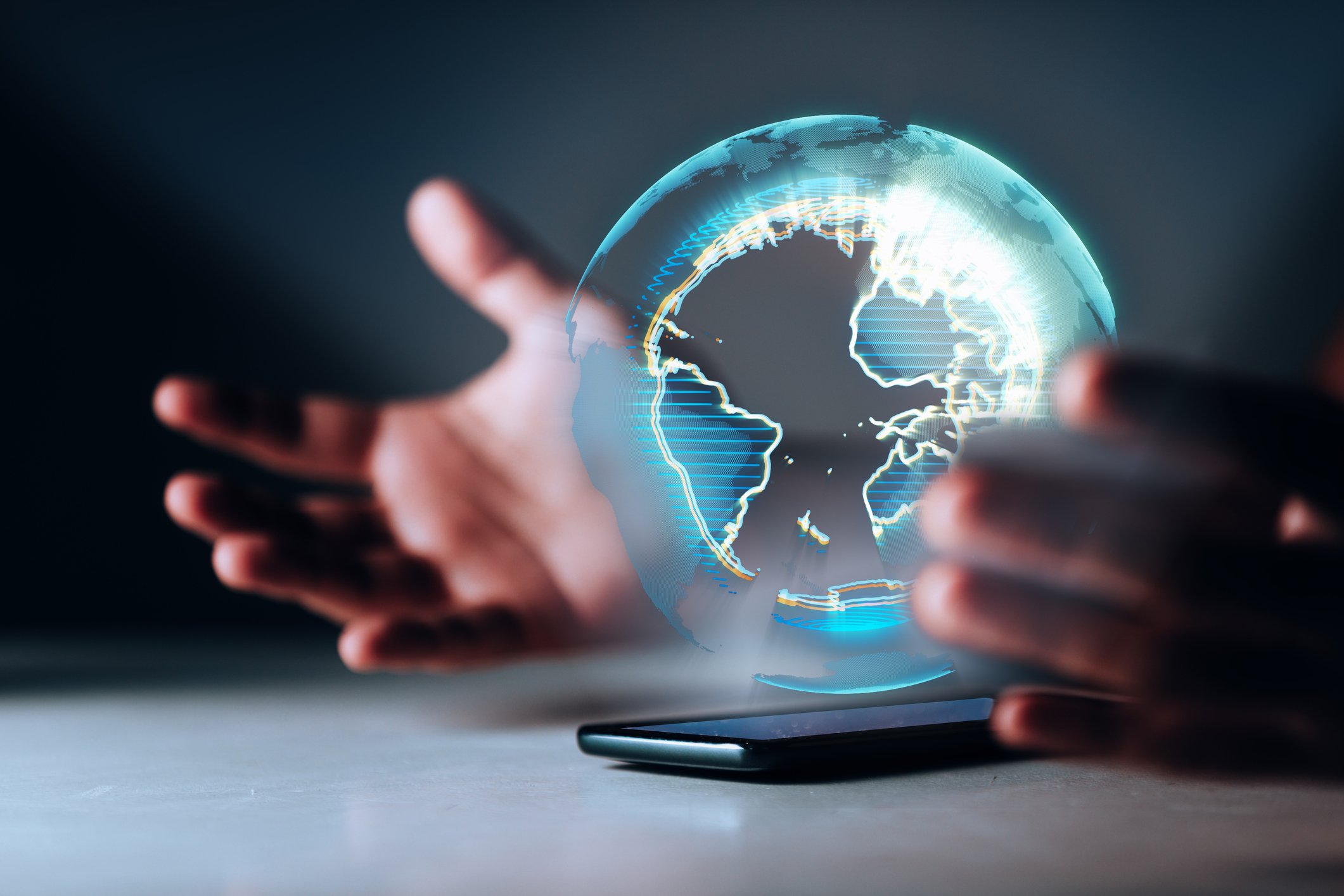 A person's hands and a mobile device displaying a globe.