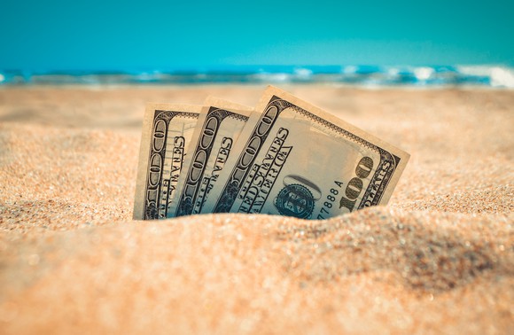 Money sticking out of the sand.