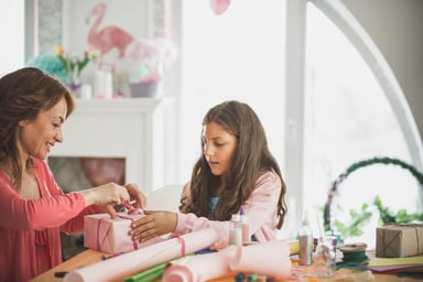 Teenager Holding Present While Mum Wraps It