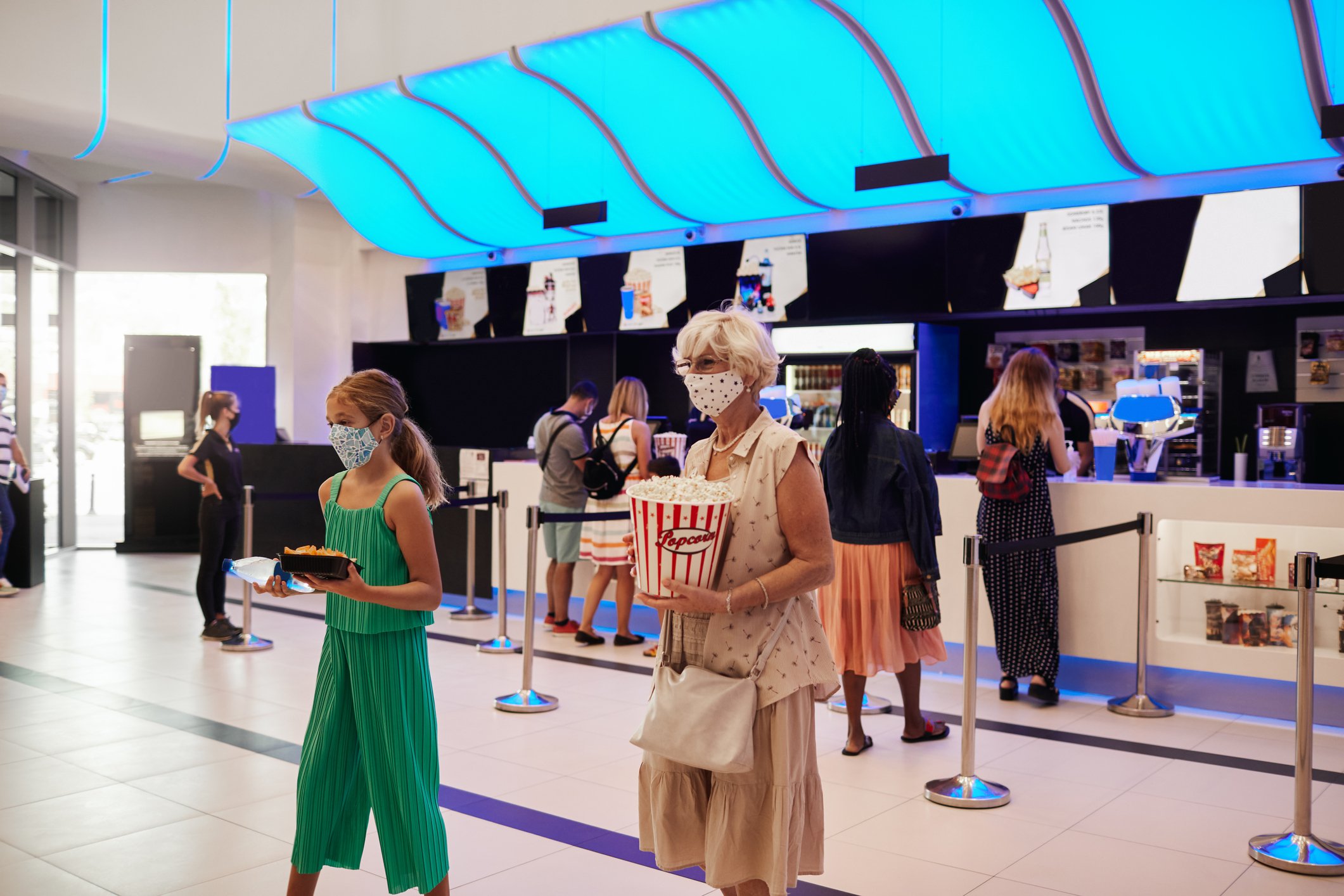 Two people walk away from a concession stand in a movie theater.