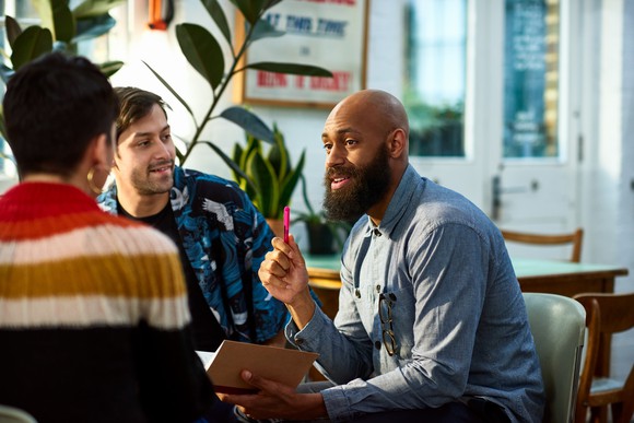 Three people talking around a table.
