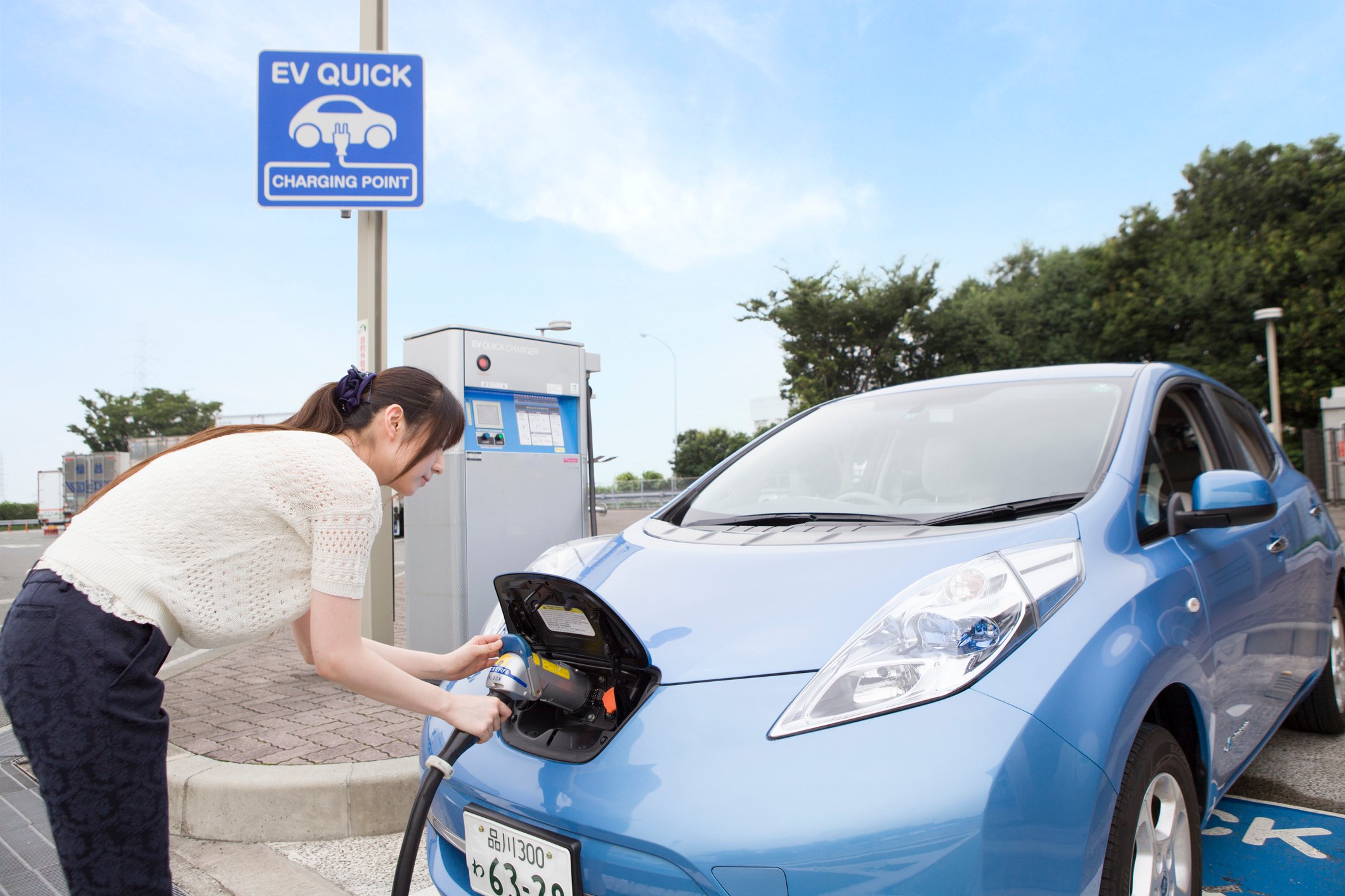 A person charging an electric car at an EV-charging station.