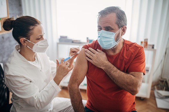 A healthcare worker vaccinates a person in a medical office.