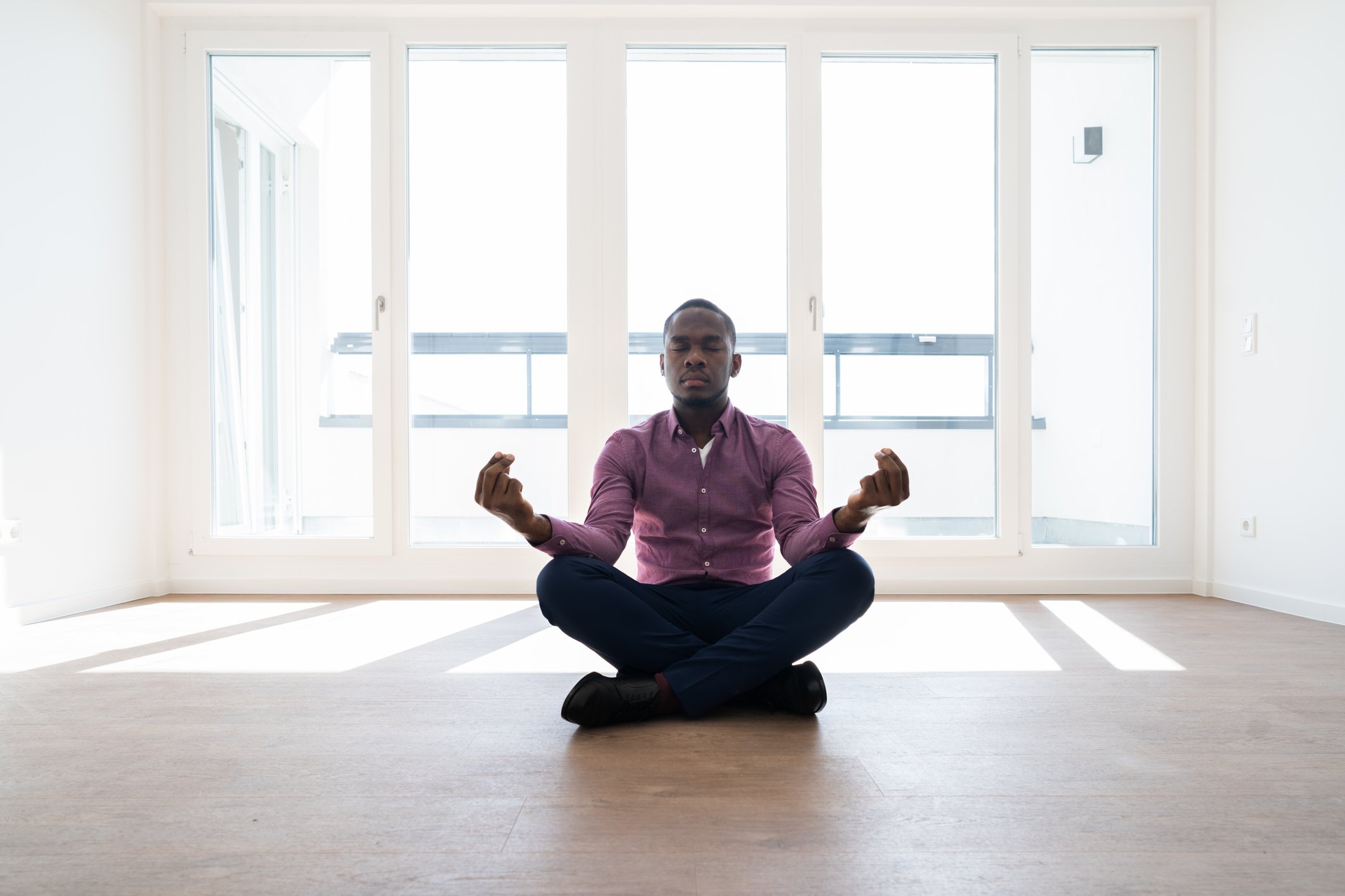 Man meditating in room filled with bright sunlight.