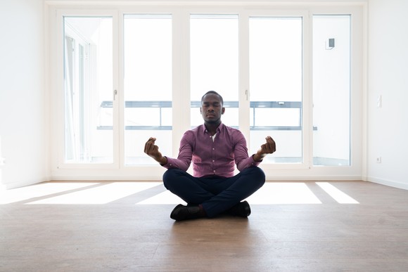 Man meditating in room filled with bright sunlight.