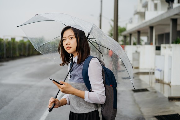 A smartphone user waits for a ride in the rain.