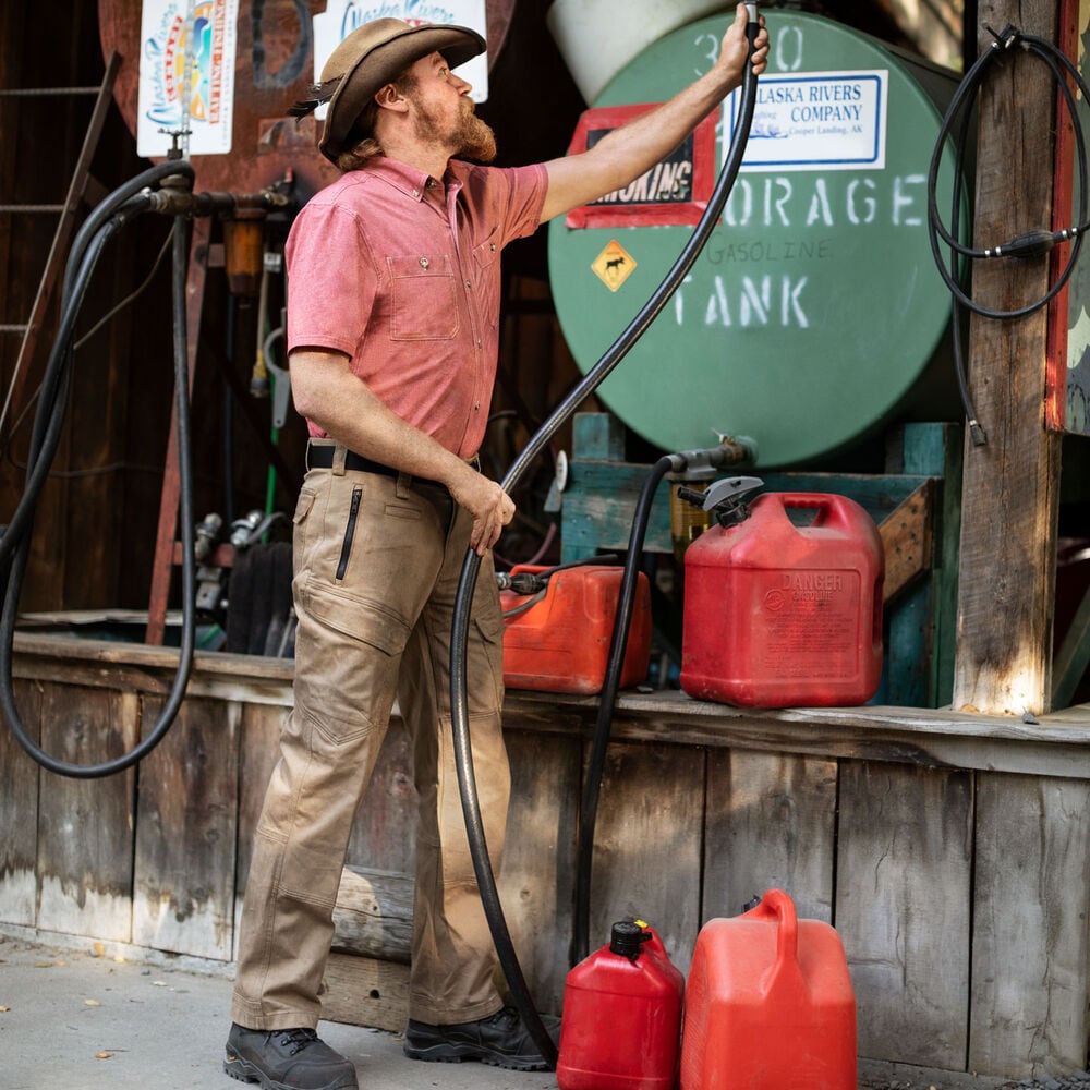 A person hooking up a hose to a storage tank.