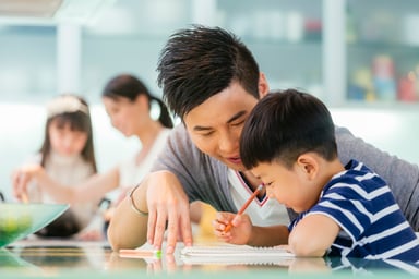 An adult tutoring a child at the kitchen table