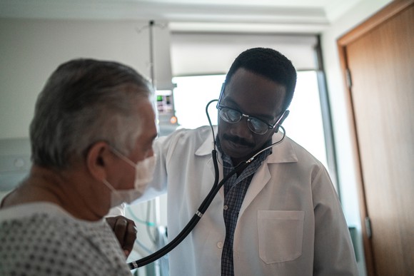 A doctor listening to a patient's heart using a stethoscope.