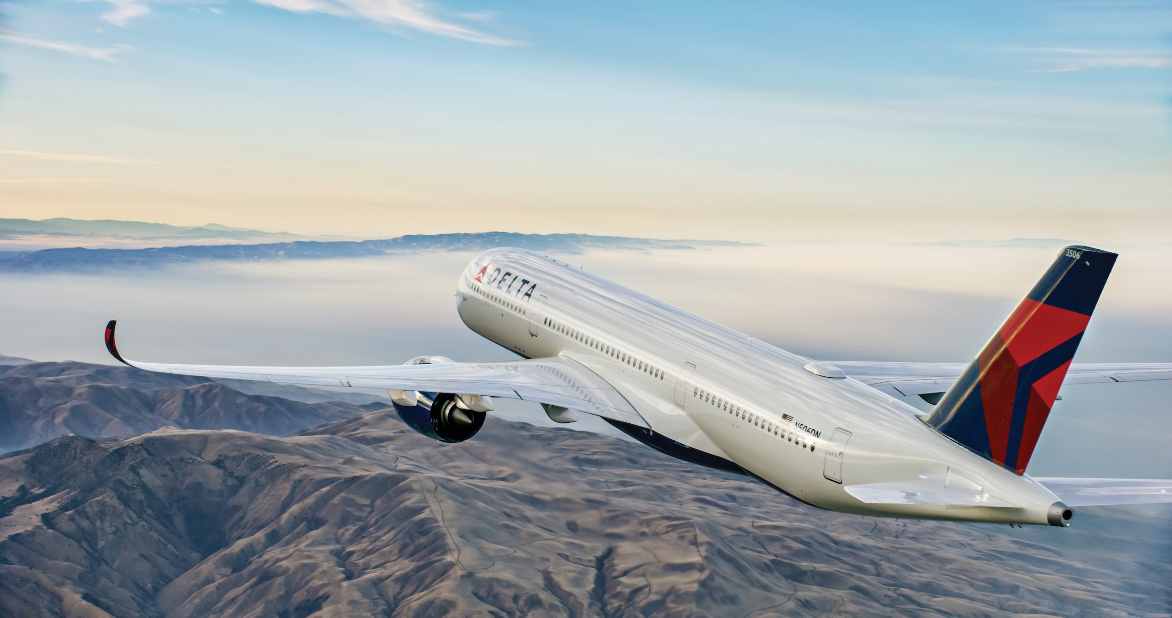 A Delta Air Lines Airbus A350 flying over mountains.
