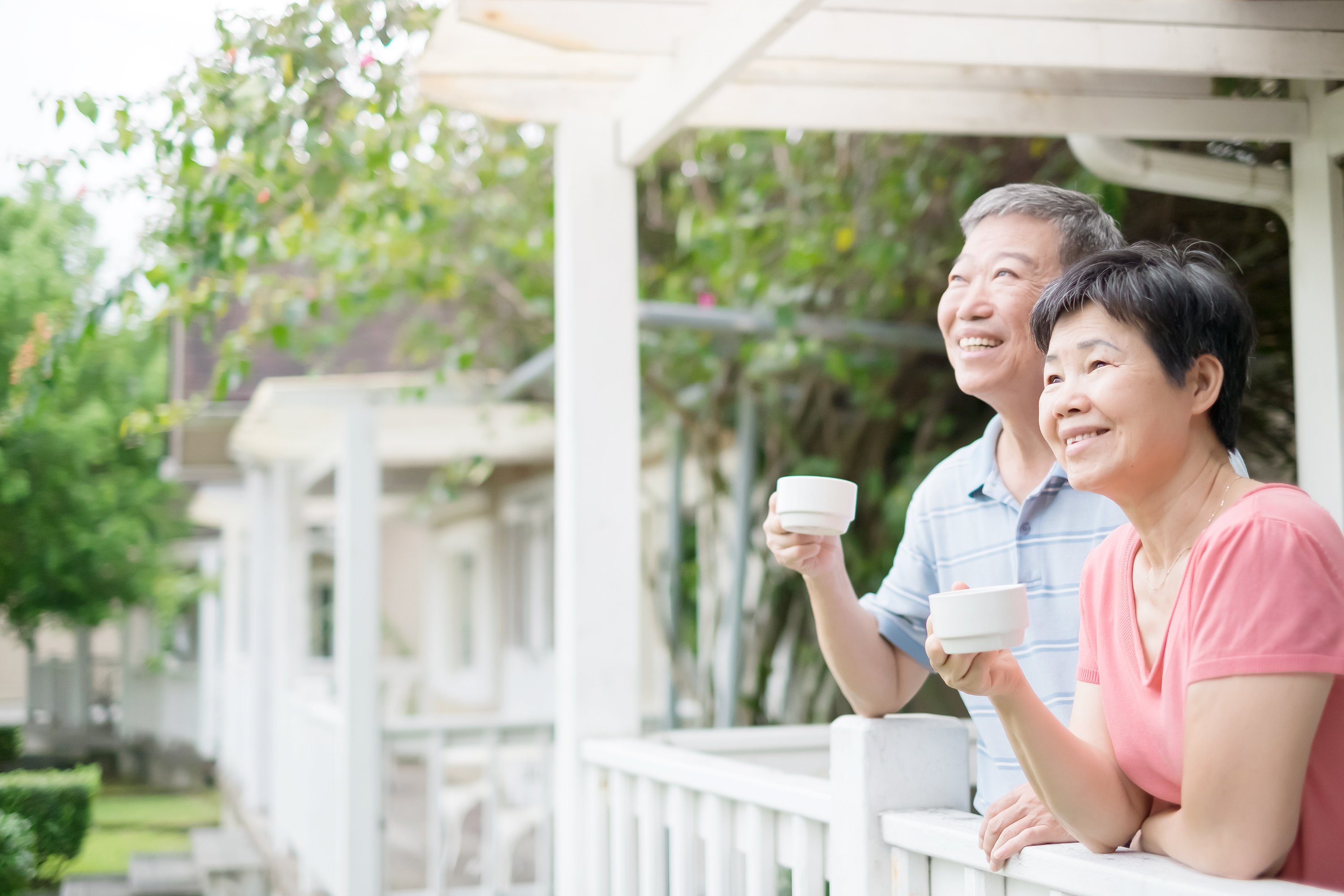 Senior couple smiling on their porch with coffee.