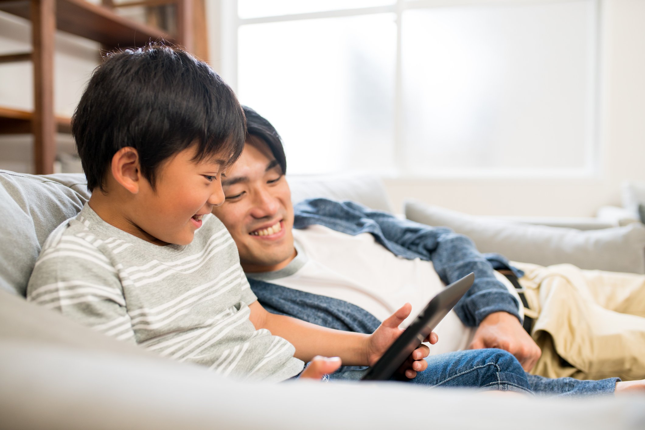 An adult and child looking at a tablet.