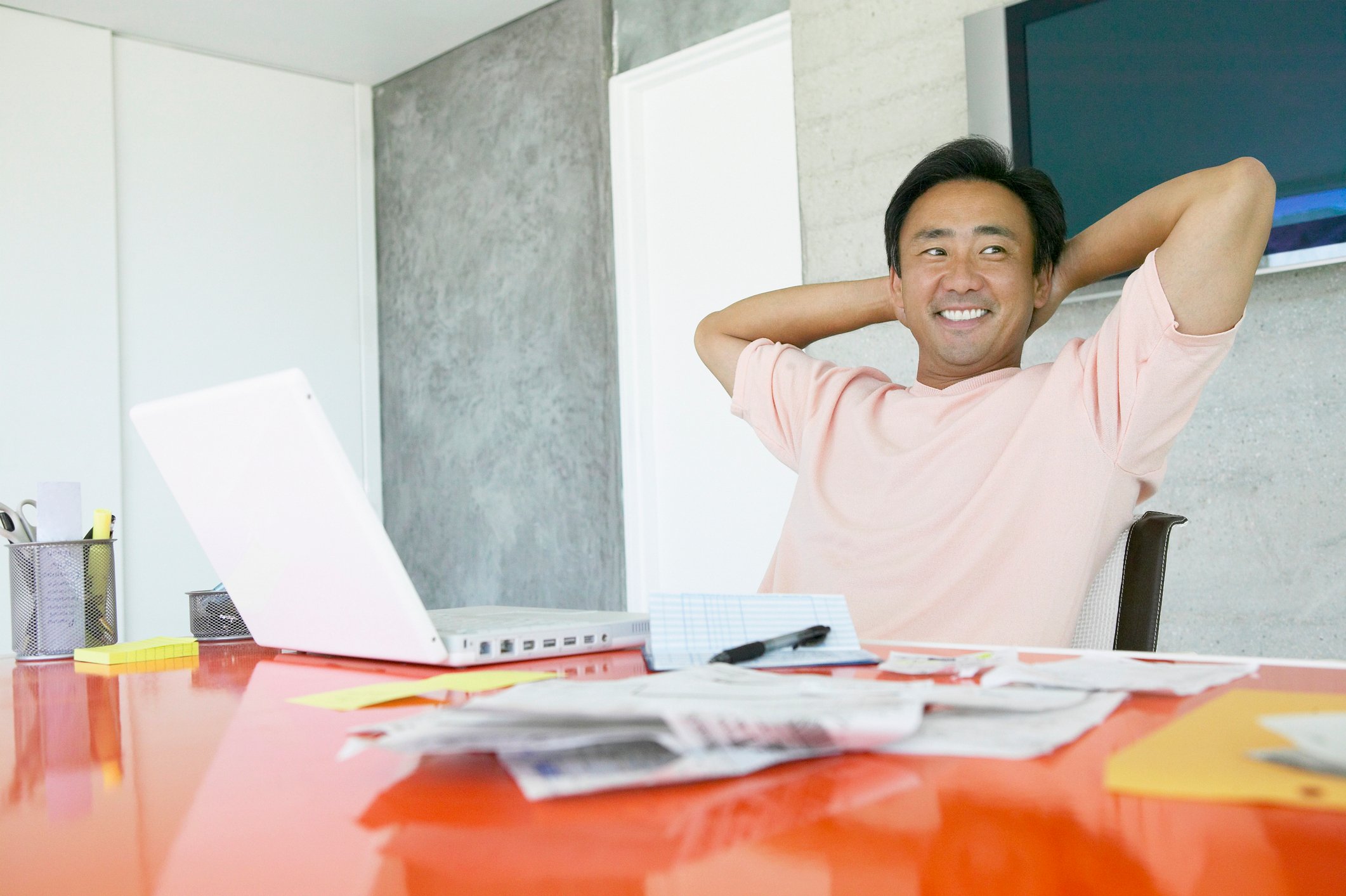 Man with hands behind head and laptop