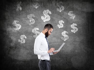Dollar signs on board behind man using laptop