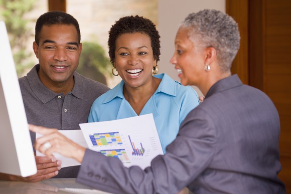People reviewing financials on a screen.