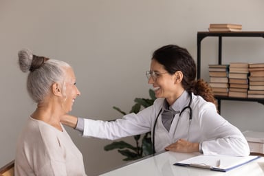 doctor smiles while touching senior patient's arm