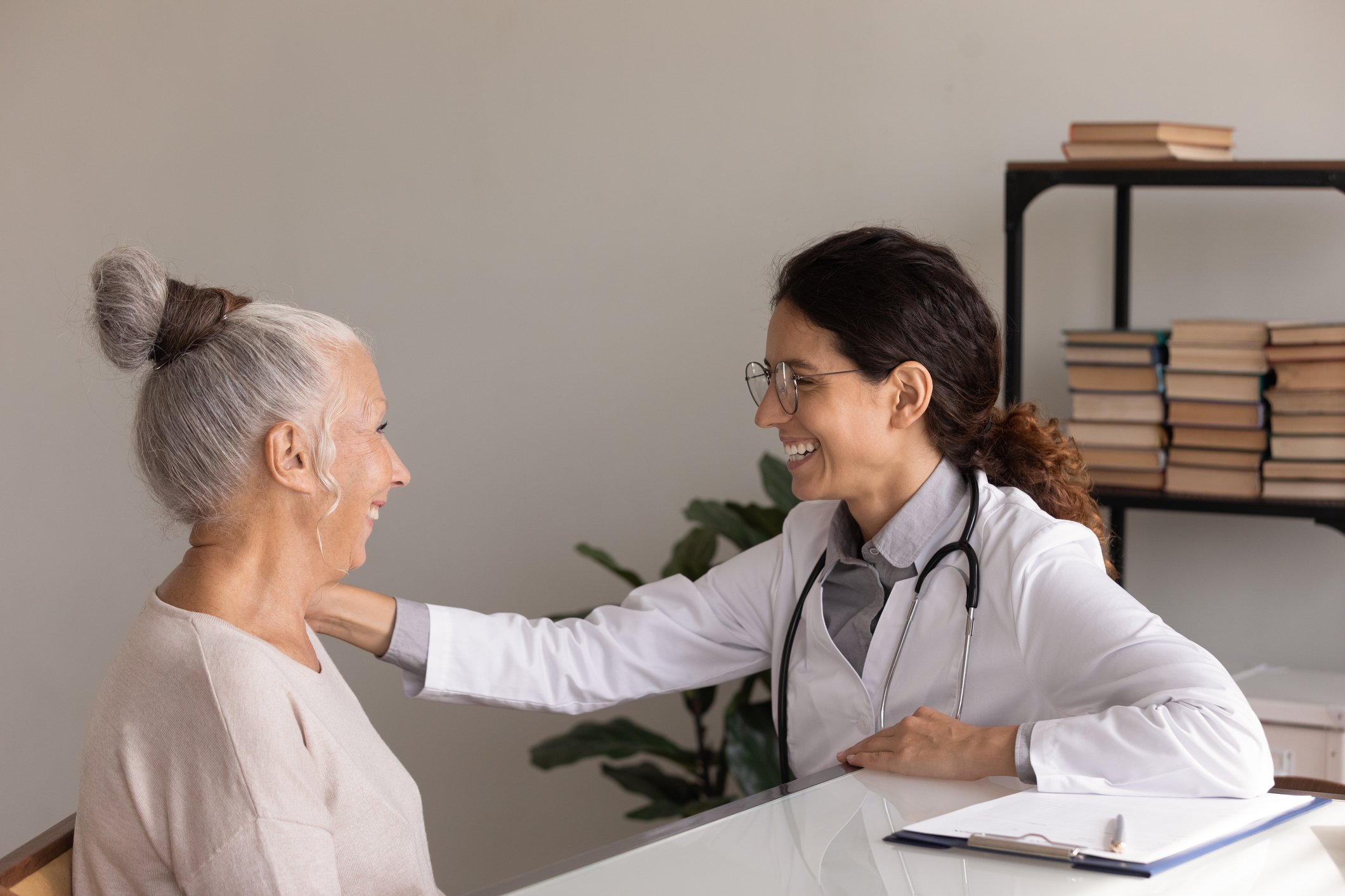doctor smiles while touching senior patient's arm