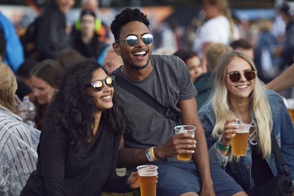 Friends having a beer together at an outdoor event.