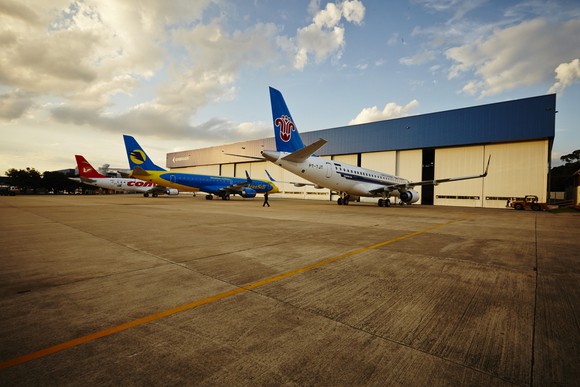 Three Embraer jets parked outside an Embraer hangar. 