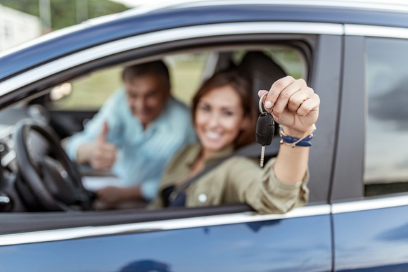 Woman in driver's seat of a car showing off the key.