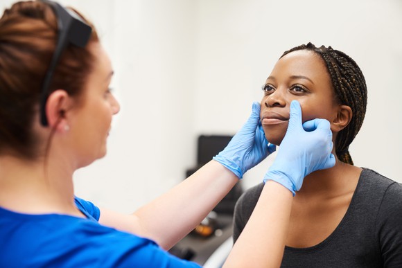 Female patient having her face checked by a medical professional.