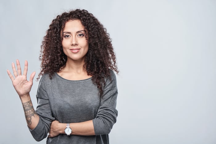 Smiling woman showing five fingers.