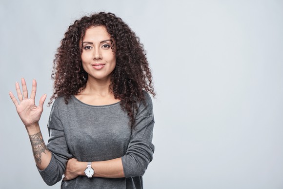 Smiling woman showing five fingers.