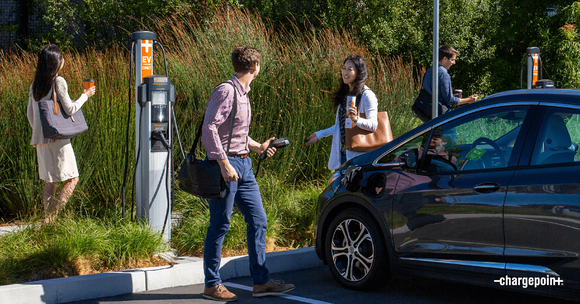 Employees socializing in front of electric vehicle chargers