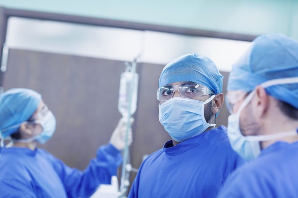 A surgeon and their staff prepare to perform a procedure on a patient.