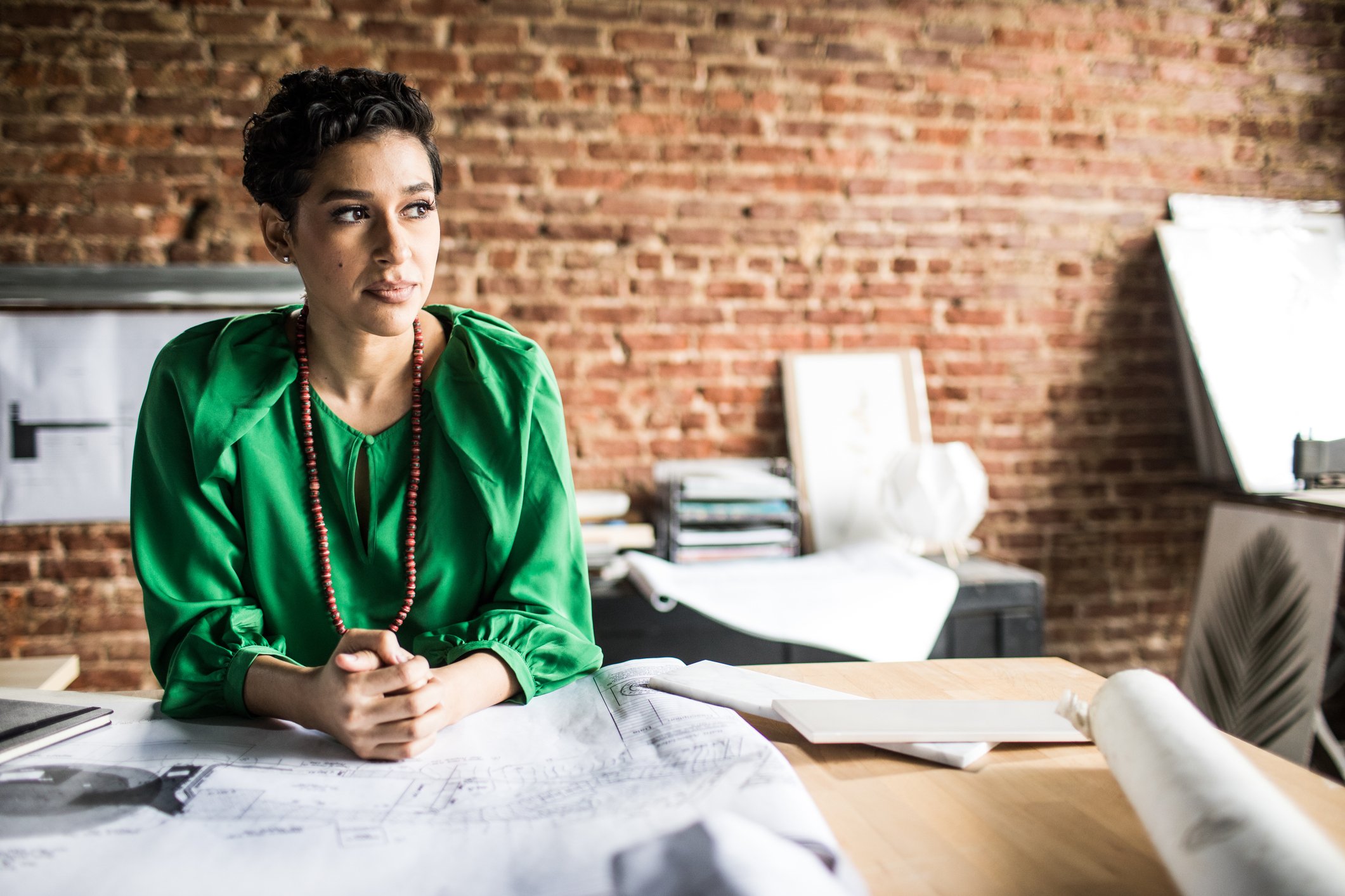 A person sits at a desk that is holding a large blueprint.