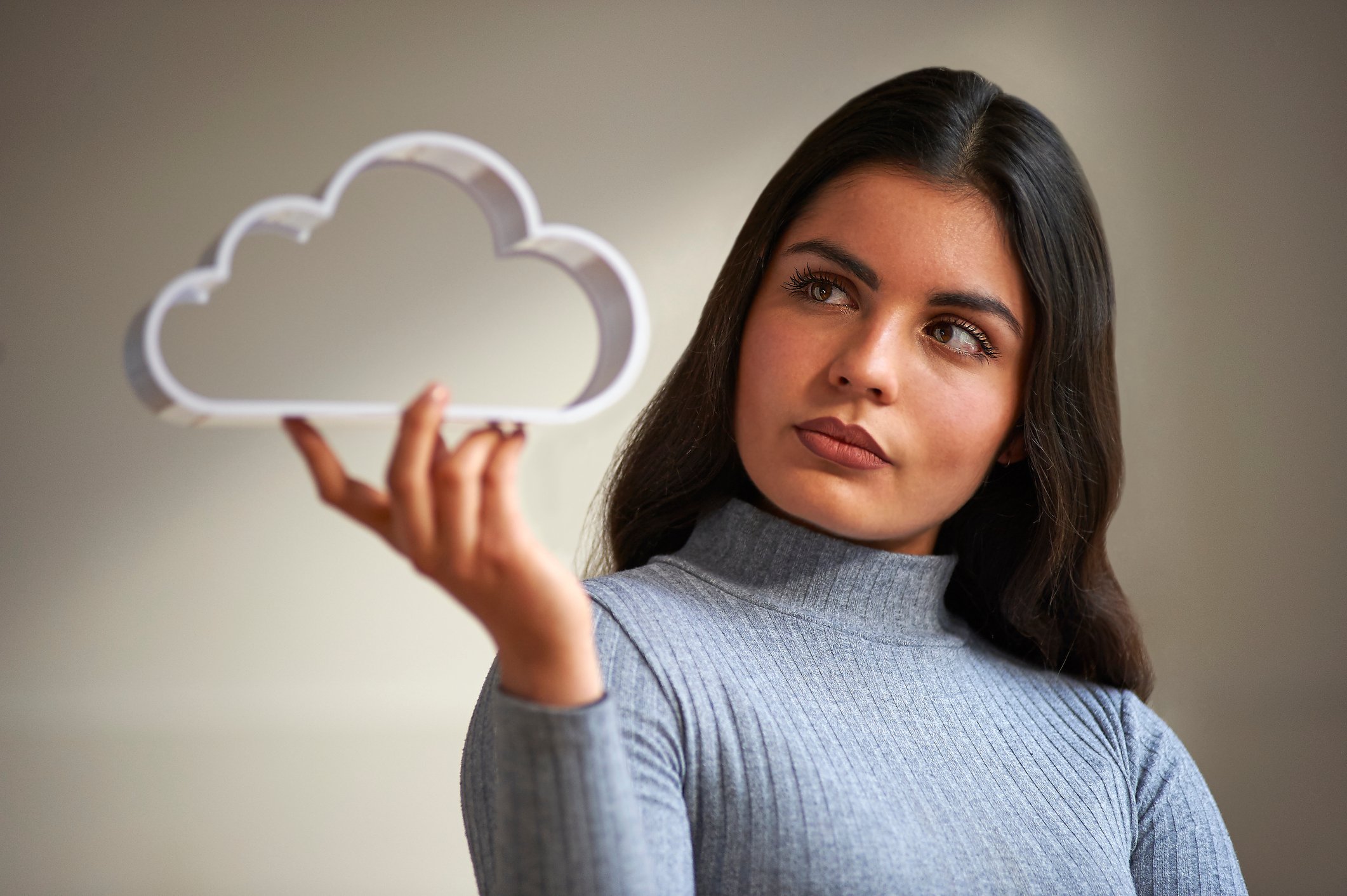 A person holds an object shaped like a cloud.
