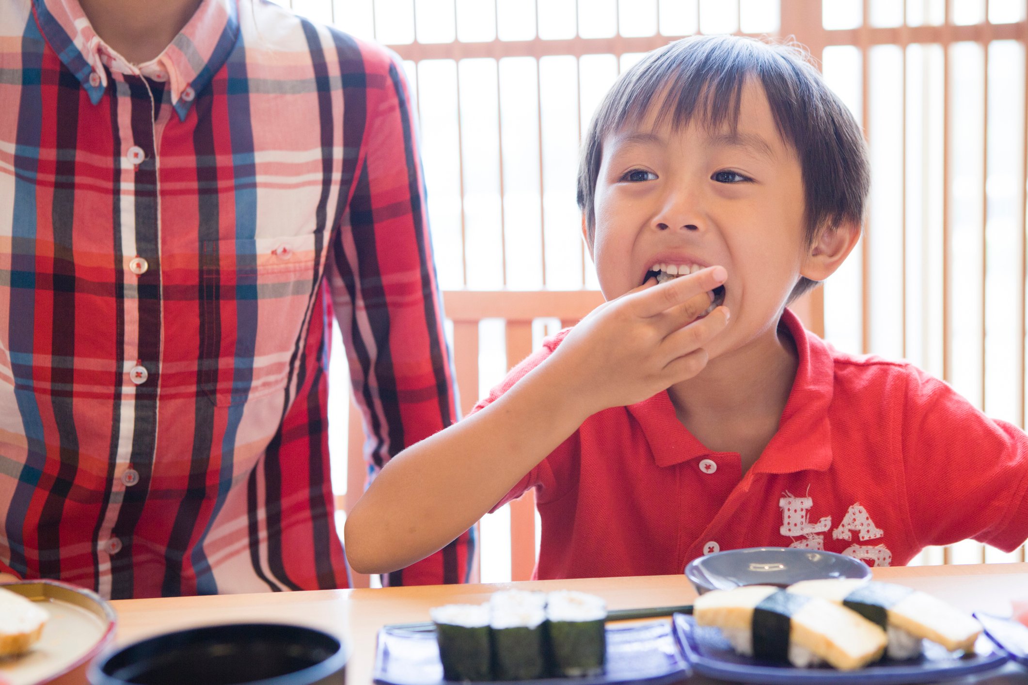 Young boy enjoying a sushi meal.