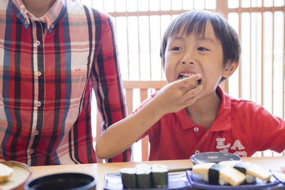 Young boy enjoying a sushi meal.