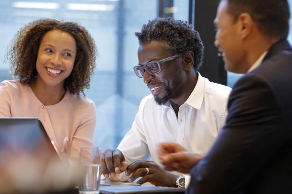 Two smiling people meeting with a financial advisor. 