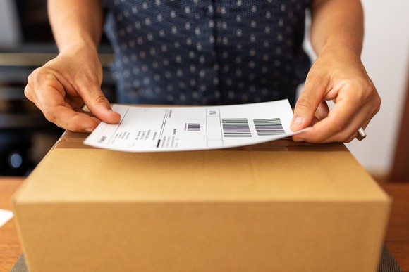 A person attaches a large label to a box.