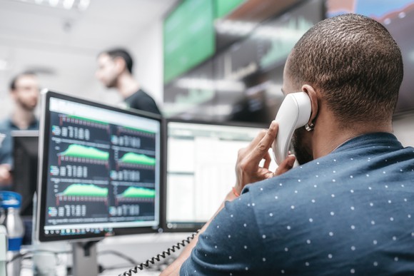 A bond trader is on the phone with economic data on the computer in front of him.