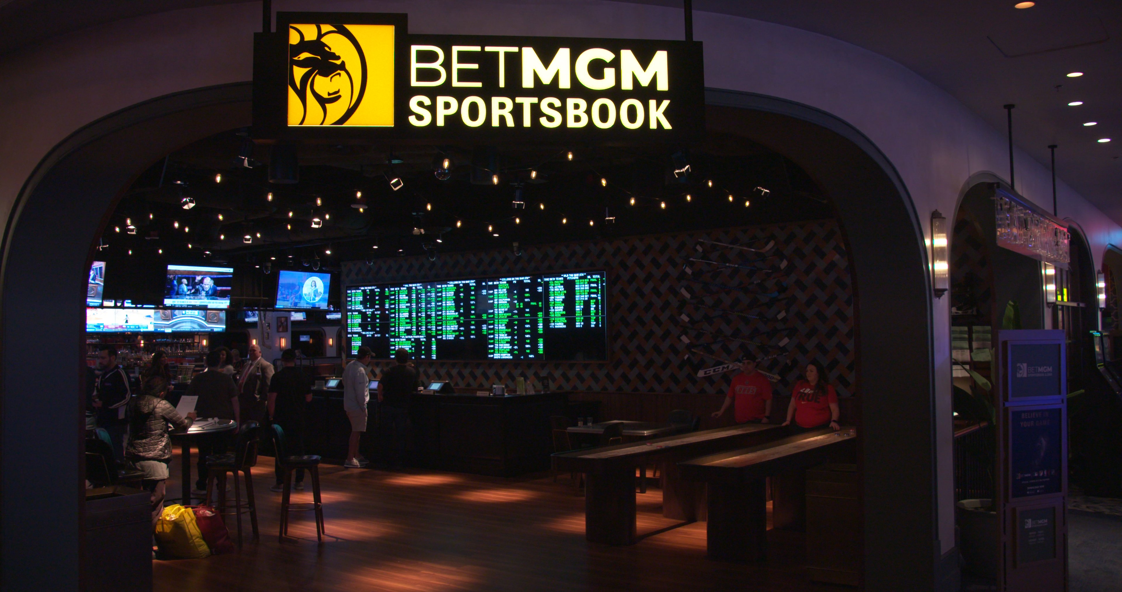 A BetMGM sportsbook with screens, benches and tables.