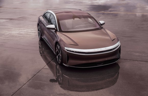 The Lucid Air sedan in brown on a damp pavement. 