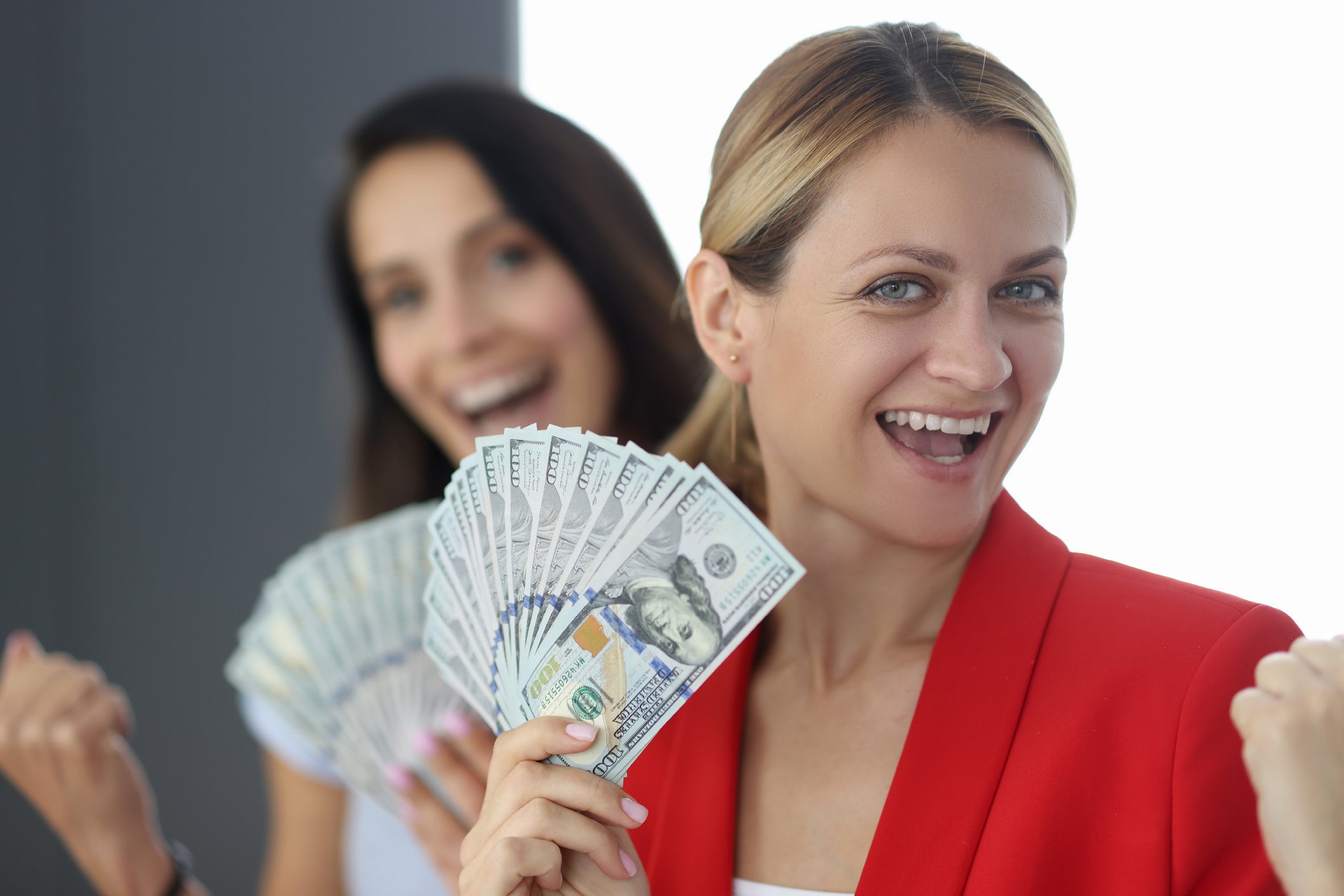 Two women holding cash that is fanned out.
