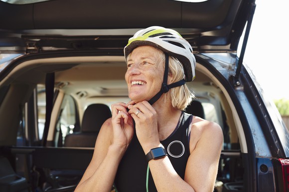 A woman wearing a smartwatch while preparing to go biking.