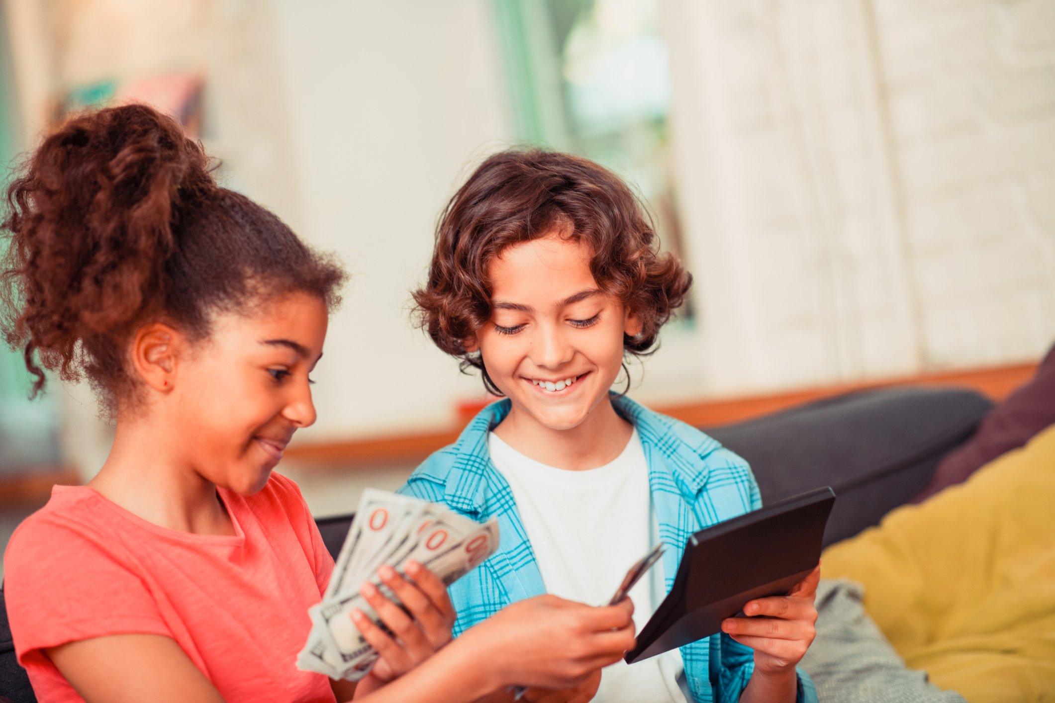 Two children holding cash and a calculator.