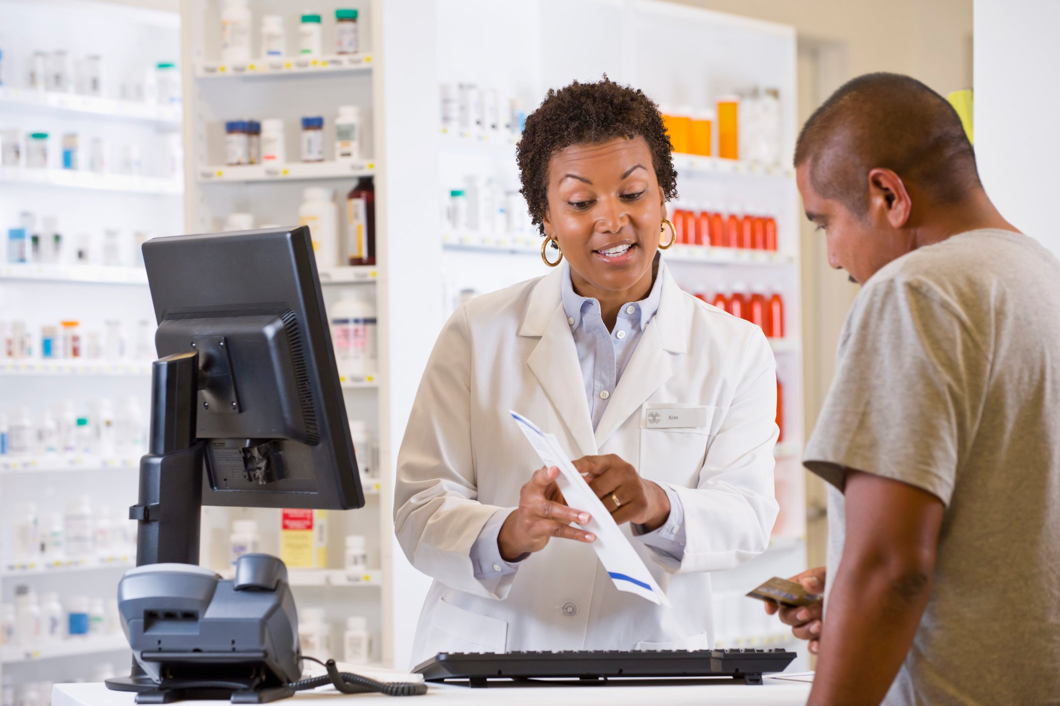 A pharmacist shows a customer his prescription information.