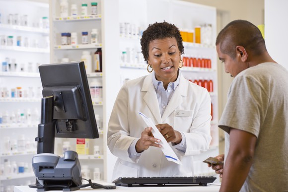 A pharmacist shows a customer his prescription information.