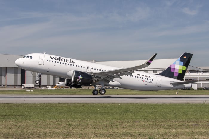 A Volaris plane landing on a runway.