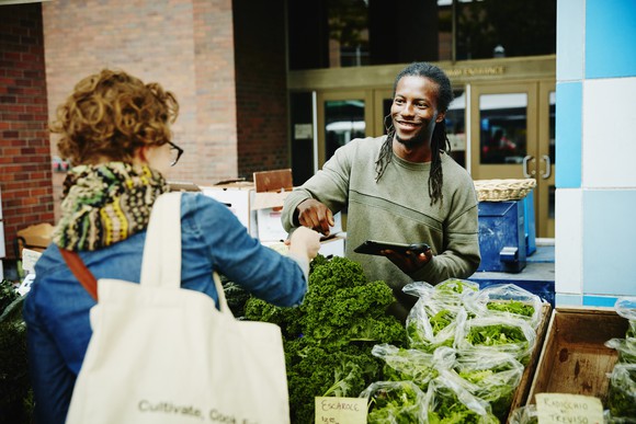 A farmer takes a credit card payment at a market.
